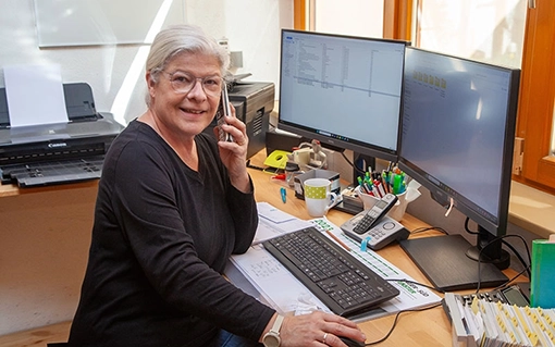 Mitarbeiterin sitzt vor einem PC und telefoniert